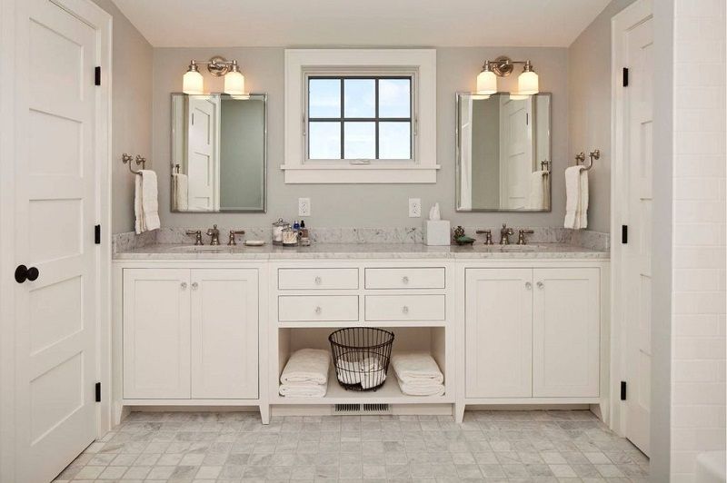 a bathroom with white cabinets and mirrors