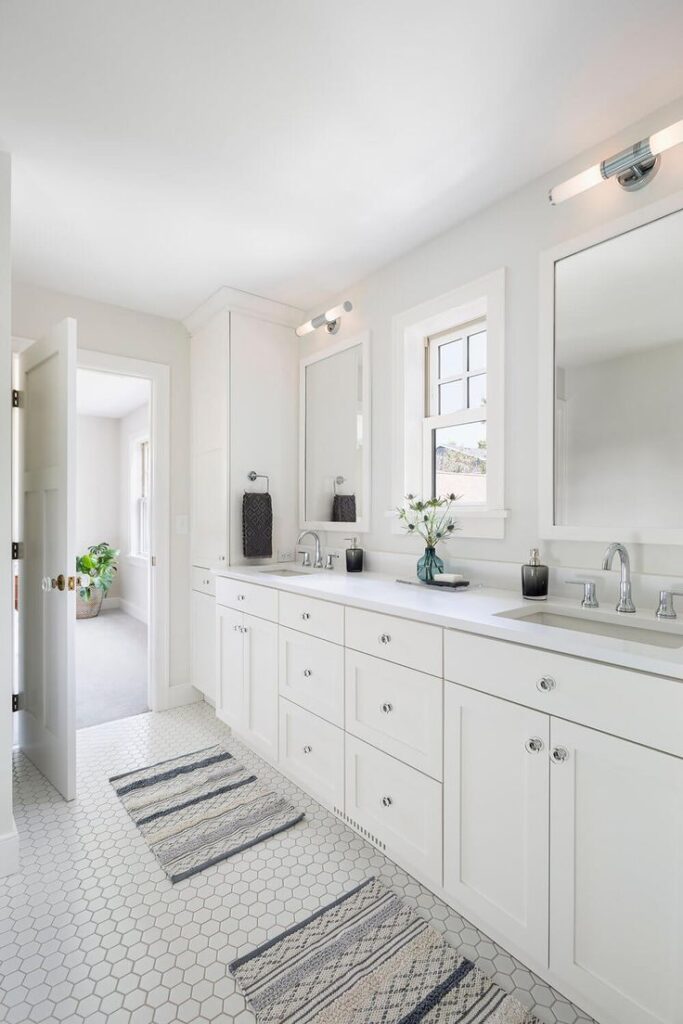 a bathroom with white cabinets and white rugs